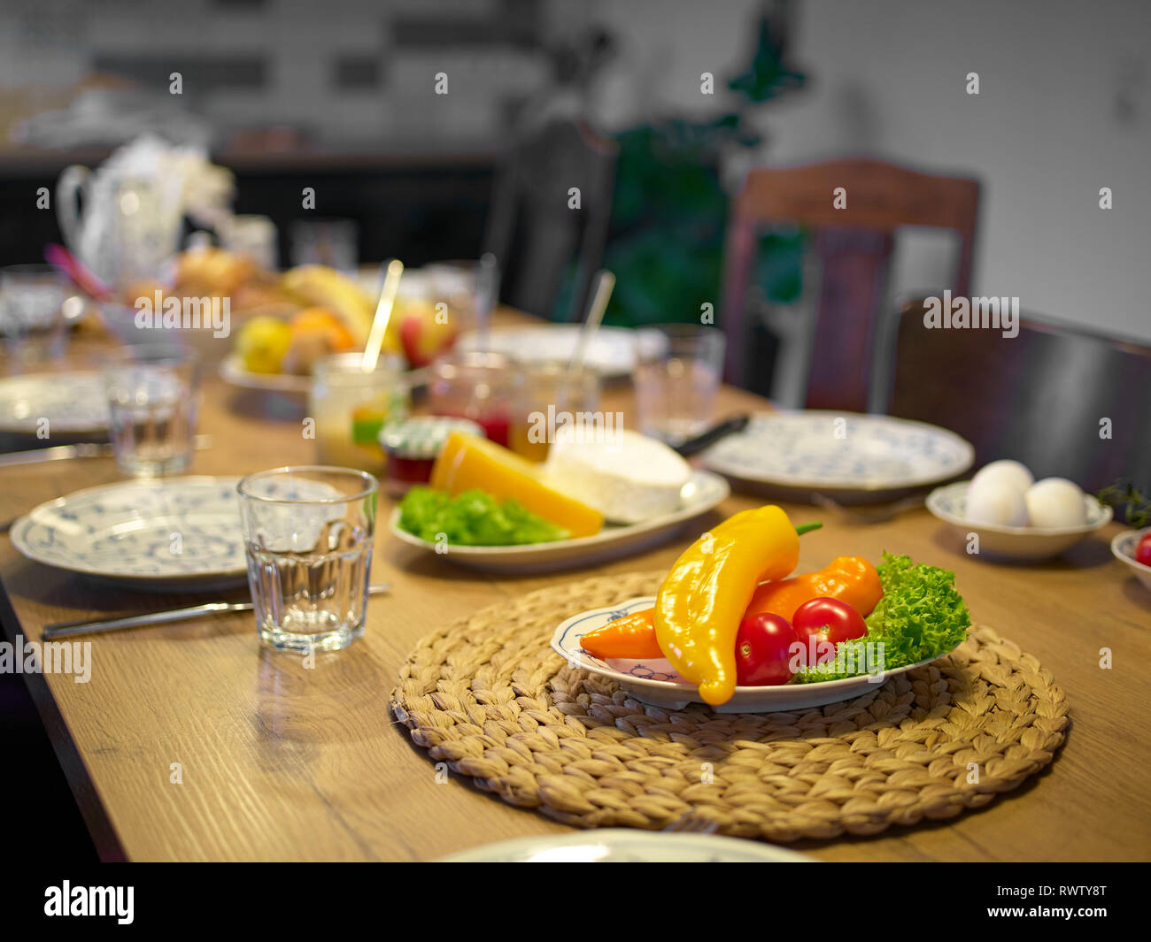 Tavolo di legno fissato per la prima colazione con frutta e verdura, inceppamento nella parte anteriore di una cucina, concentrarsi sui peperoni in primo piano Foto Stock