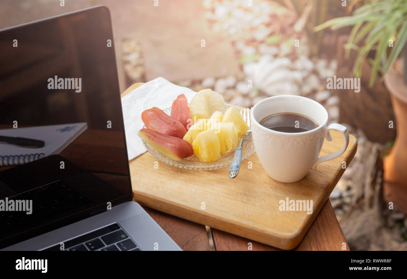 Tazza da caffè con frutta fresca e portatile sul tavolo di legno nel  giardino Foto stock - Alamy