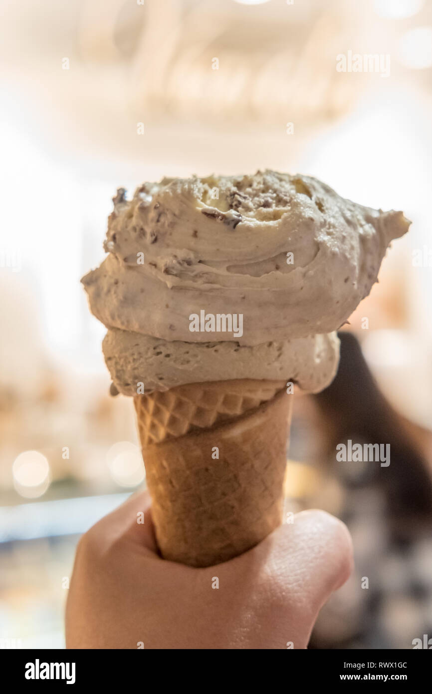 Mano che regge il gelato al cioccolato, gelato con sfocatura dello sfondo. Foto Stock