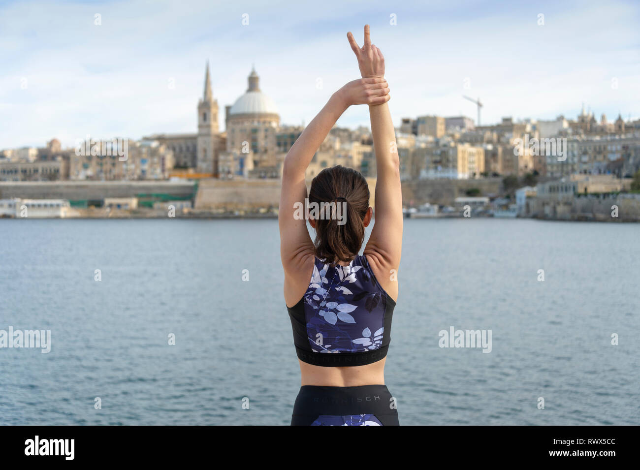 Donna in piedi di fronte a La Valletta, Malta, con le braccia aperte, libertà di viaggio. Foto Stock