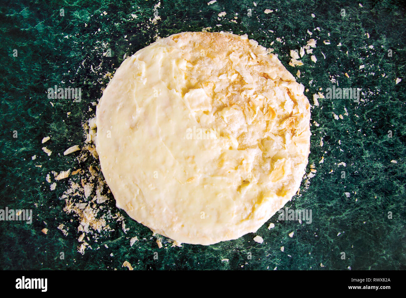 Round layered Napoleone torta con crema pasticcera e cosparso briciole su una verde tavola di marmo, vista dall'alto. Il processo di cottura Dessert Ricetta. Foto Stock