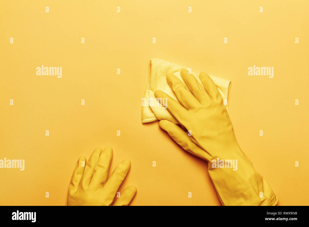 Un mani in una gomma di guanto protettivo con una spugna bianca su sfondo giallo. Il concetto di pulizia. Foto Stock