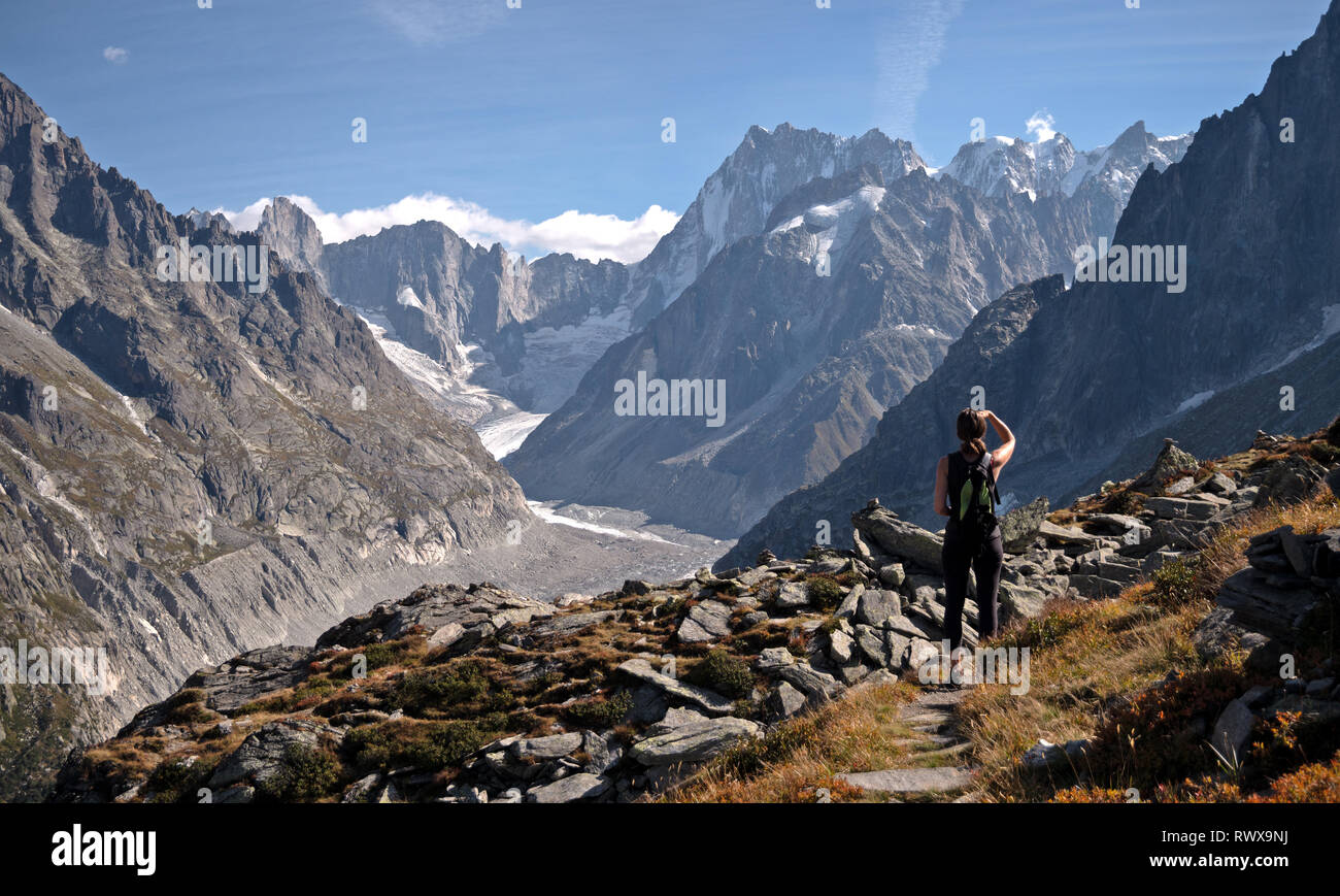 Un solitario escursionista femmina si affaccia su un ghiacciaio valle nella regione di Chamonix nelle alpi della Francia. Foto Stock
