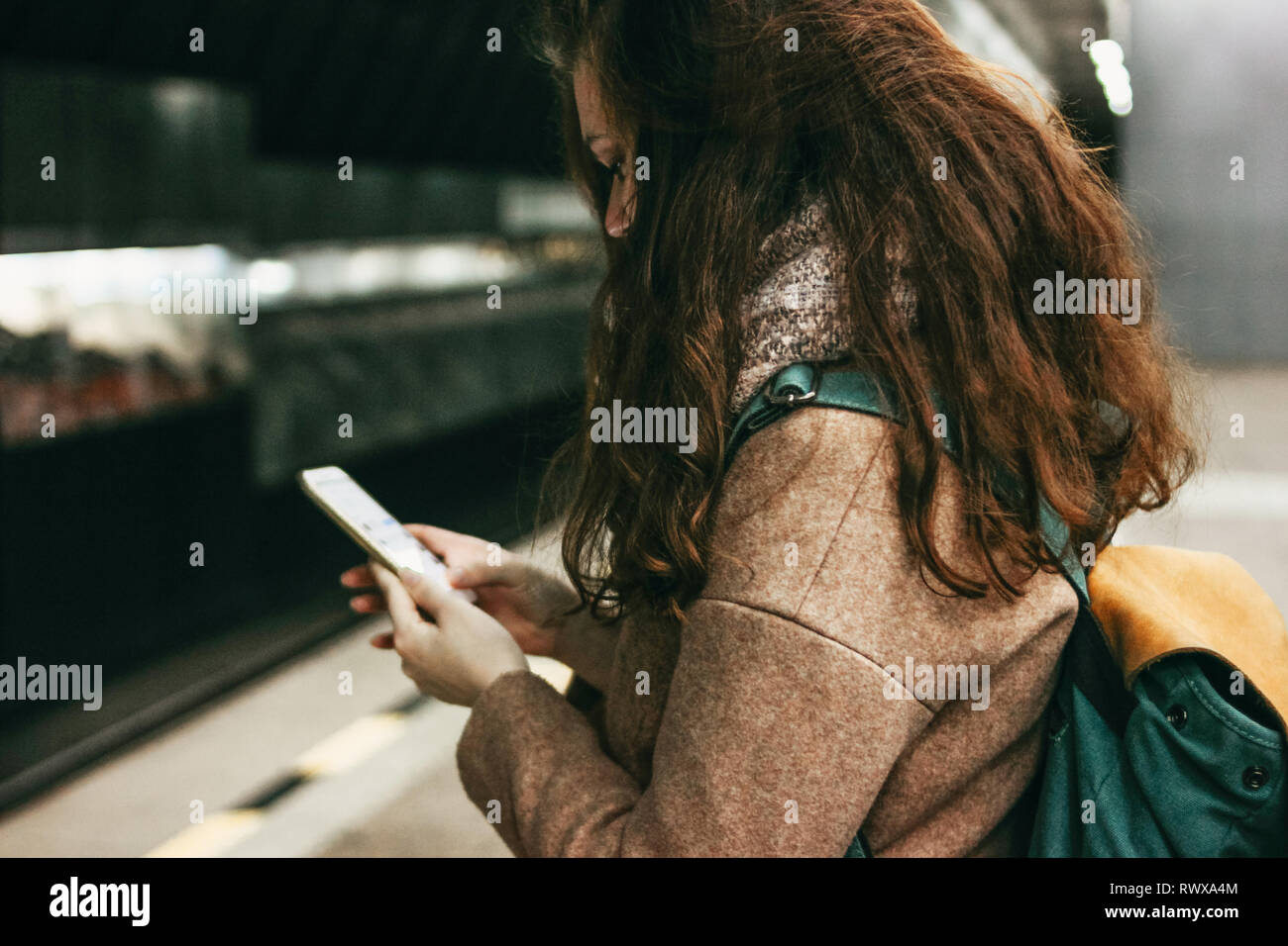 Giovane donna ricci testa rossa ragazza viaggiatori con zaino utilizzando mobile in metropolitana Foto Stock