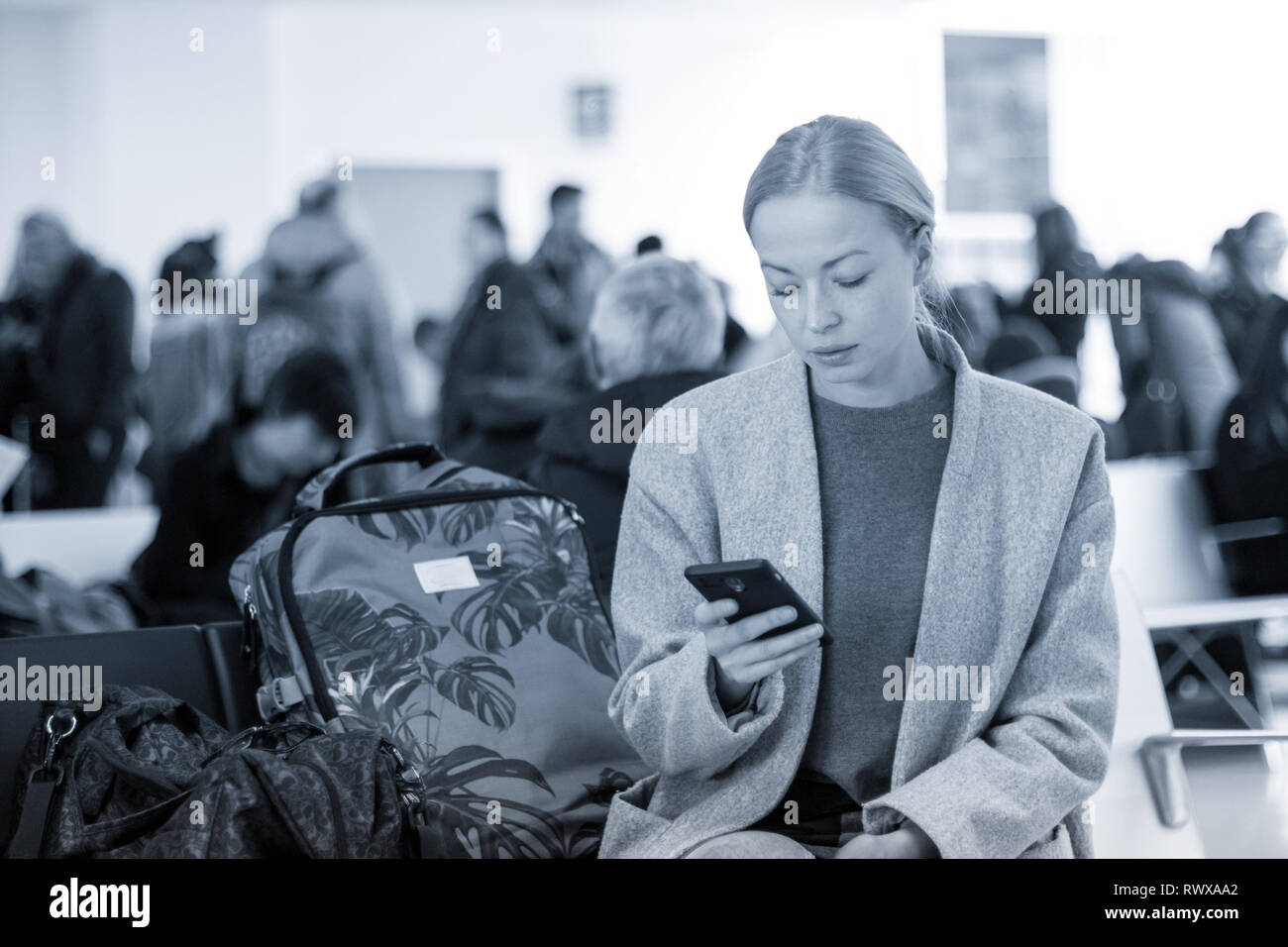 Viaggiatori femmina la lettura sul suo telefono cellulare mentre si è in attesa di salire a bordo di un aereo a cancelli di partenza al terminal aeroportuale. Foto Stock