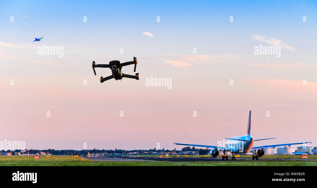 Drone senza pilota battenti vicino alla pista di atterraggio all'aeroporto mentre aereo commerciale decolla portando ad una possibile collisione - digital composite. Foto Stock