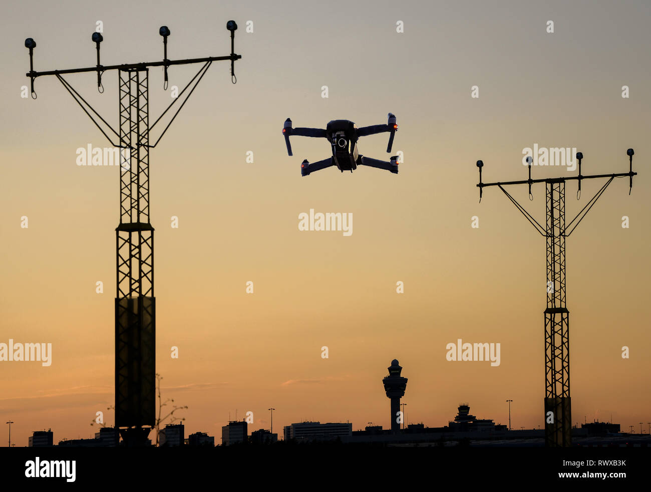 Drone senza pilota battenti vicino alla pista di aeroporto in avvicinamento tra illuminazione della pista al tramonto. Foto Stock