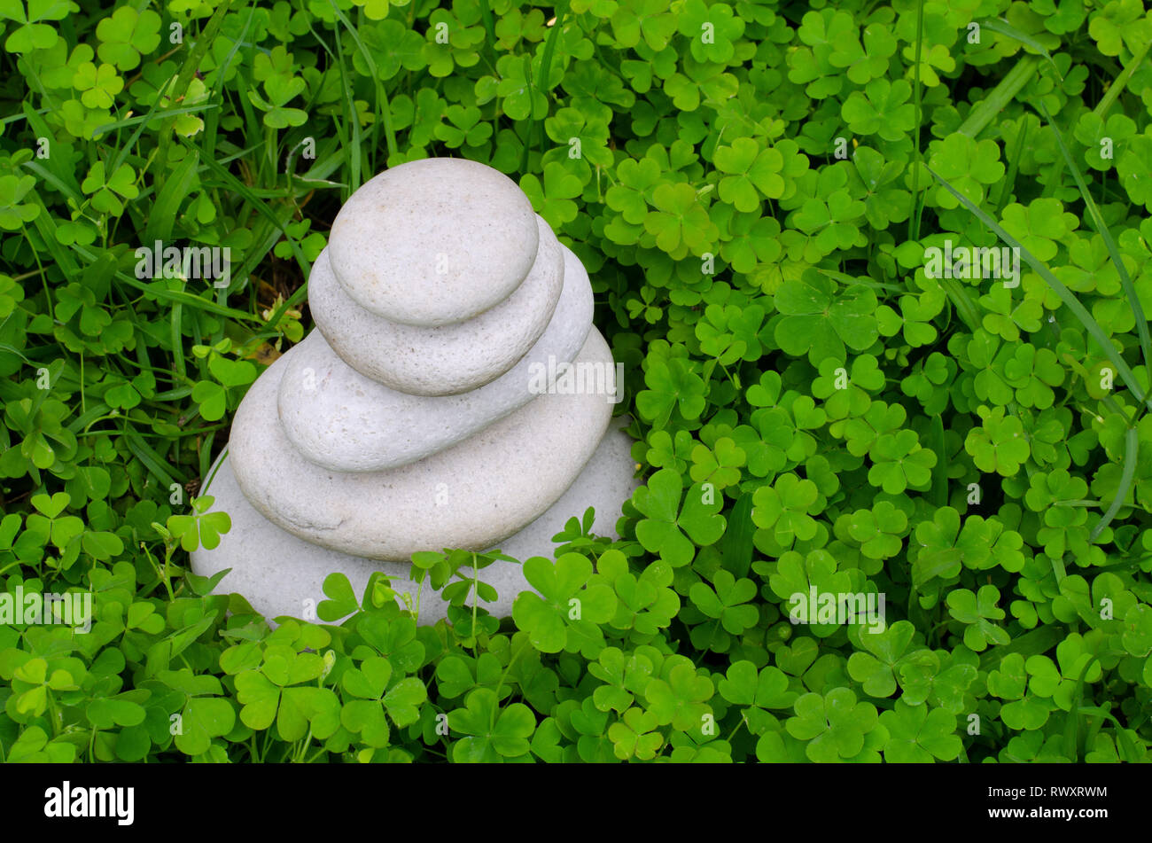 Una pietra cairn di gradualmente eroso ciottoli in un lussureggiante verde letto di trifoglio. Foto Stock