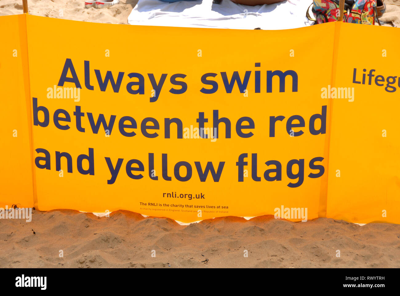 RNLI banner sulla spiaggia di consigliare ' sempre nuotare tra il giallo e il rosso bandiere", Port Eynon, Galles Foto Stock
