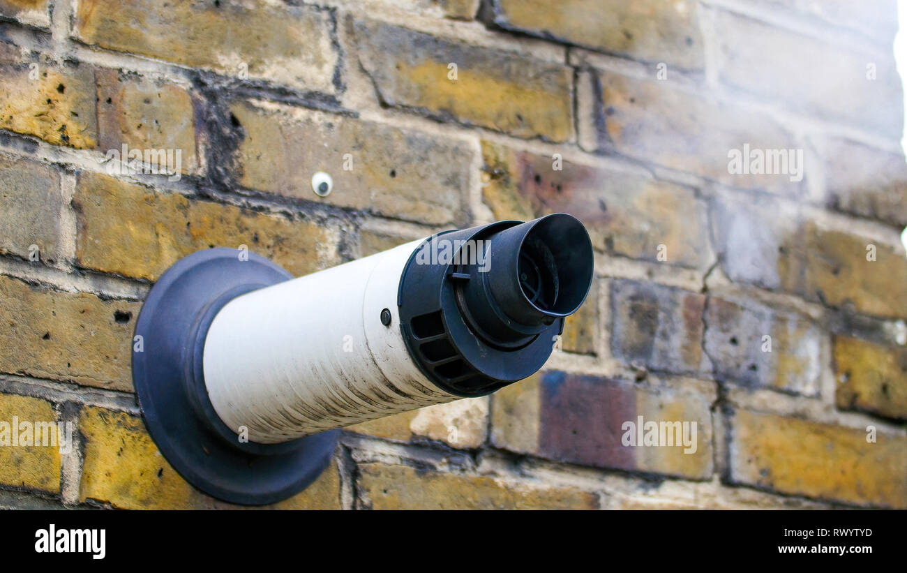 Un vapore che fuoriesce da una ventilazione in una parete. Il fumo bianco che esce dal vapore può proviene dall'edificio all'interno Foto Stock