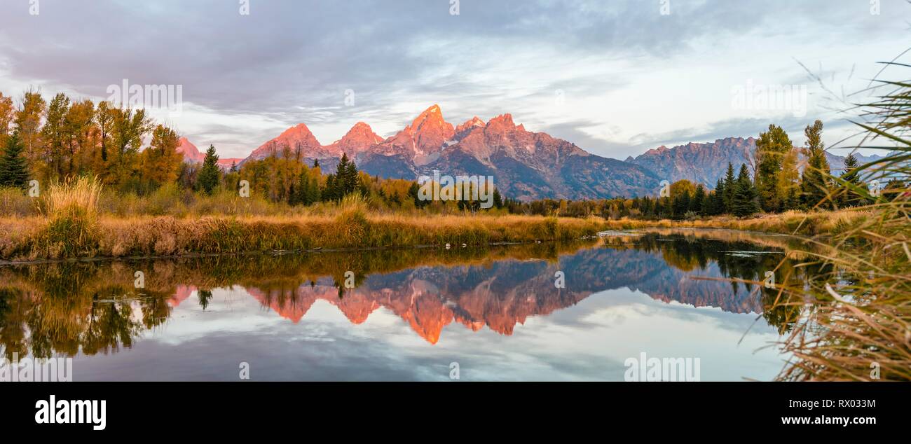 Montagne brillare rosso di sunrise, Grand Teton Range gamma di montagna si riflette nel fiume, paesaggio autunnale su Snake River Foto Stock