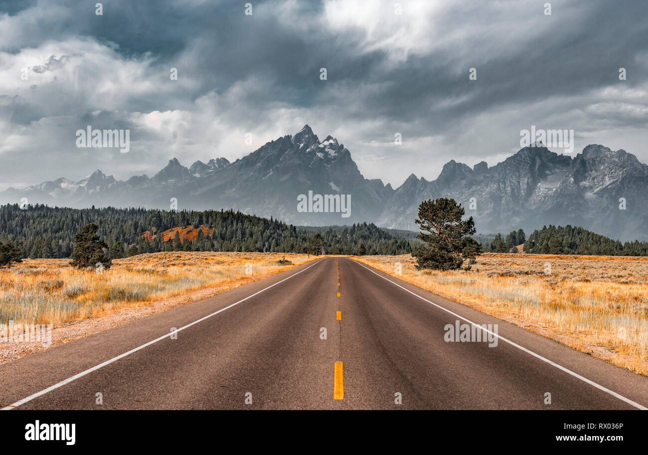 Autostrada nella parte anteriore delle aspre montagne con cielo nuvoloso, Grand Teton Range, il Parco Nazionale del Grand Teton, Wyoming USA Foto Stock