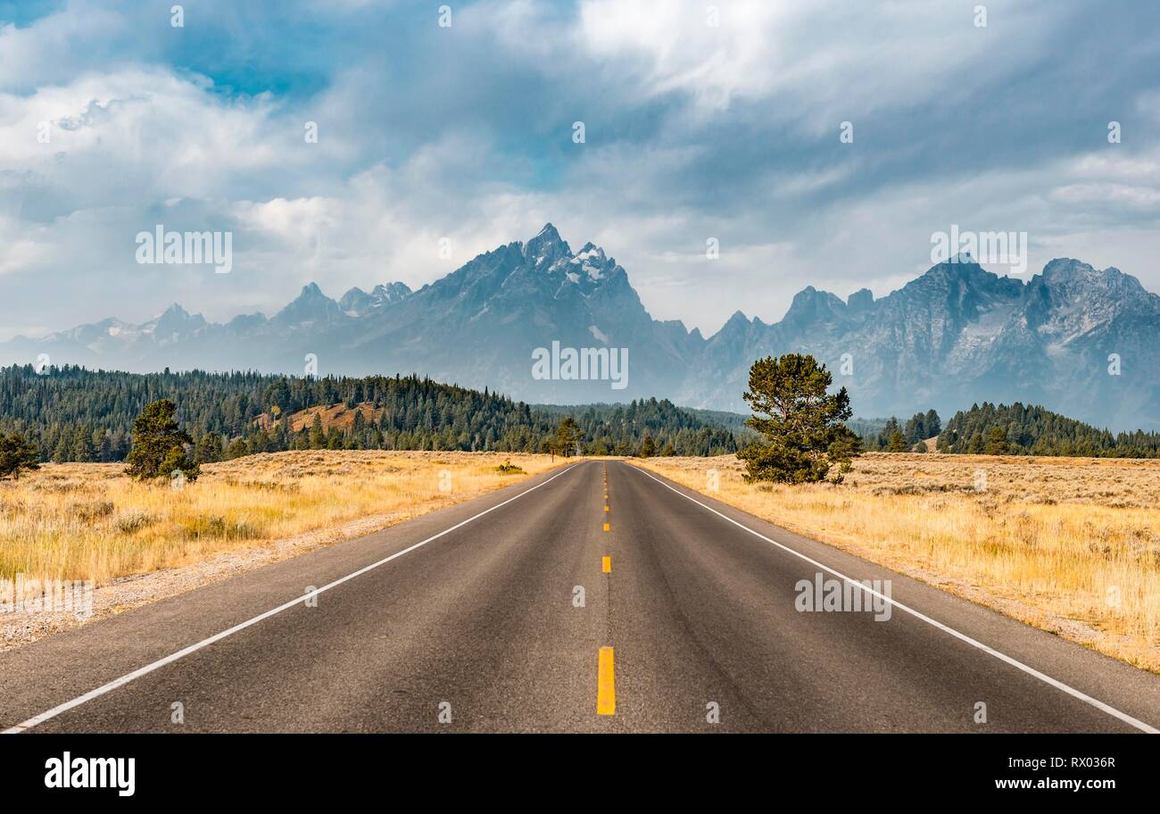 Autostrada nella parte anteriore delle aspre montagne con cielo nuvoloso, Grand Teton Range, il Parco Nazionale del Grand Teton, Wyoming USA Foto Stock