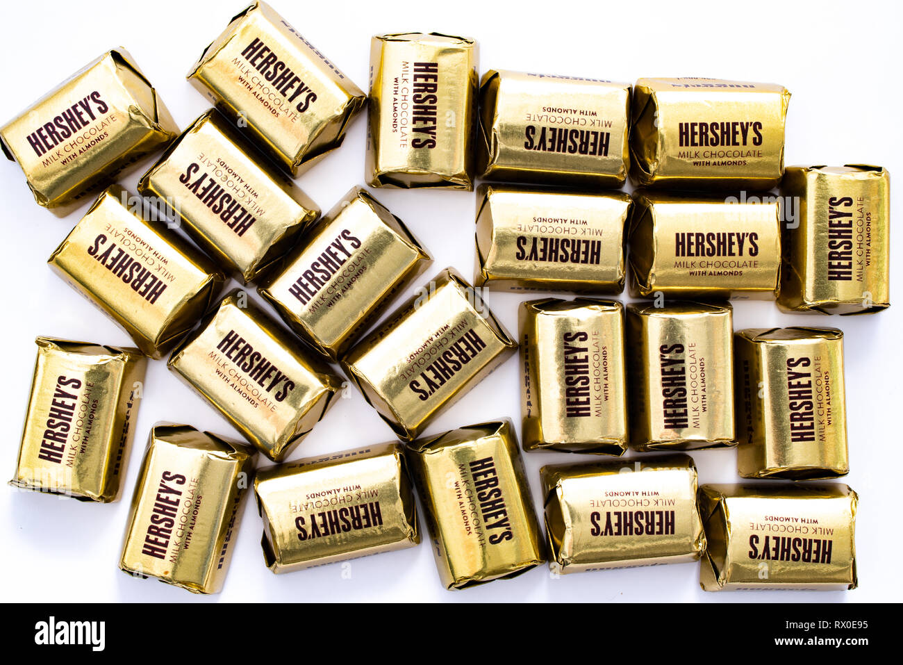 Un mucchio di Hershey's cioccolato al latte con mandorle pepite in oro individuale wrapper colorato isolato su bianco. Foto Stock