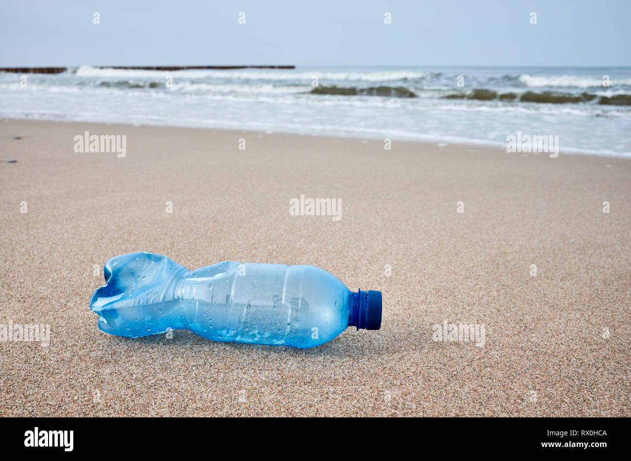 La bottiglia di plastica a sinistra su una spiaggia, il fuoco selettivo, tonificazione del colore applicato. Foto Stock