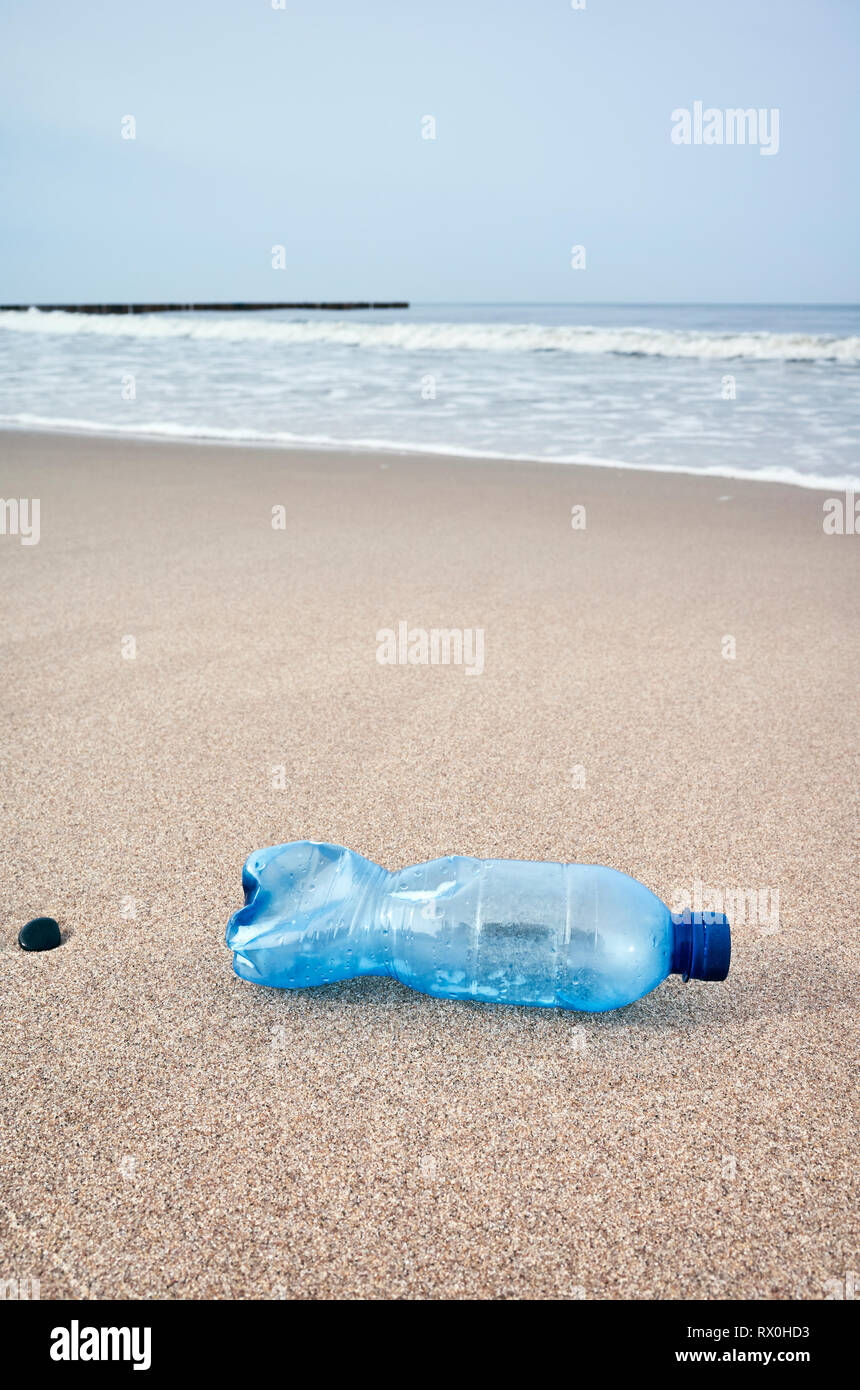La bottiglia di plastica a sinistra su una spiaggia, il fuoco selettivo, tonificazione del colore applicato. Foto Stock