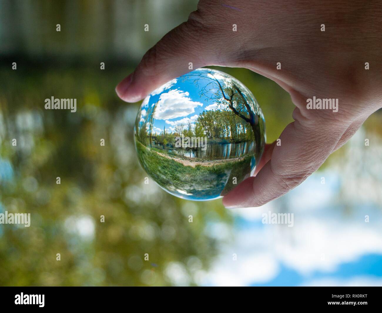Un irriconoscibile persona con una sfera di cristallo nella sua mano con un paesaggio riflesso Foto Stock