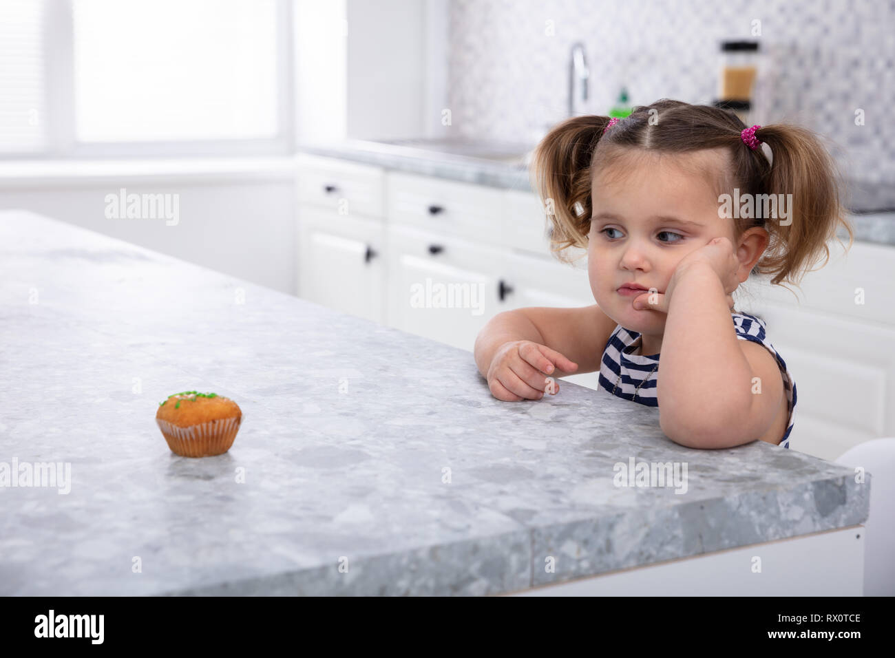 Close-up di ragazza Guardando Cupcake sul piano di lavoro della cucina Foto Stock