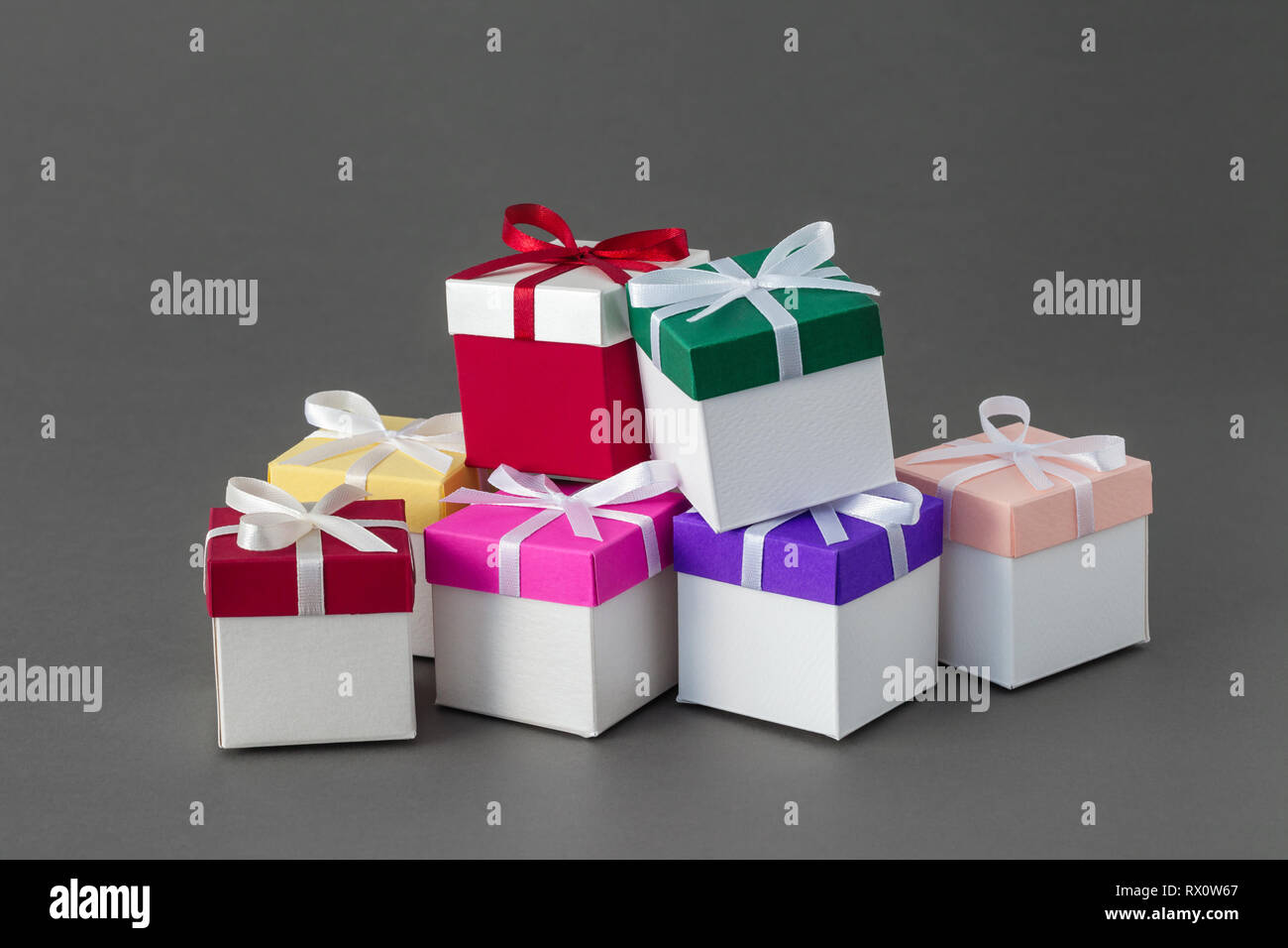 Più colorate scatole regalo con nastri su sfondo grigio. Foto Stock