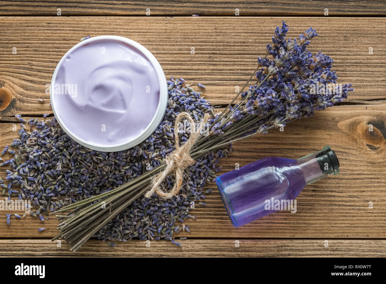 Lavanda crema o balsamo, olio essenziale, malta secca di lavanda e un mazzo di fiori secchi. Vista superiore, piatto laici. Foto Stock