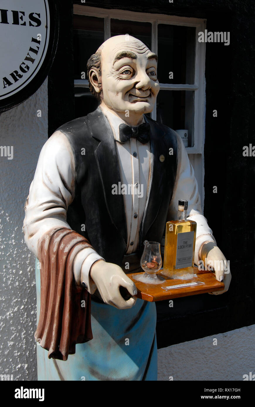 Modello a grandezza dell uomo, vestito come cameriere, in piedi fuori casa pubblica tenendo il vassoio con bottiglia di whisky e vetro, Inveraray, Scozia Foto Stock