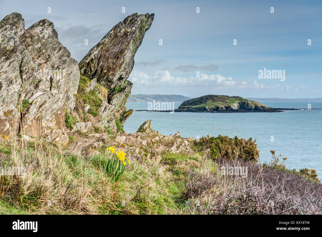 Una fotografia di Looe isola nel sud-est della Cornovaglia incorniciati da rocce a ponte sul sud-ovest sentiero costiero guardando oltre verso Downderry sulla costa. Foto Stock