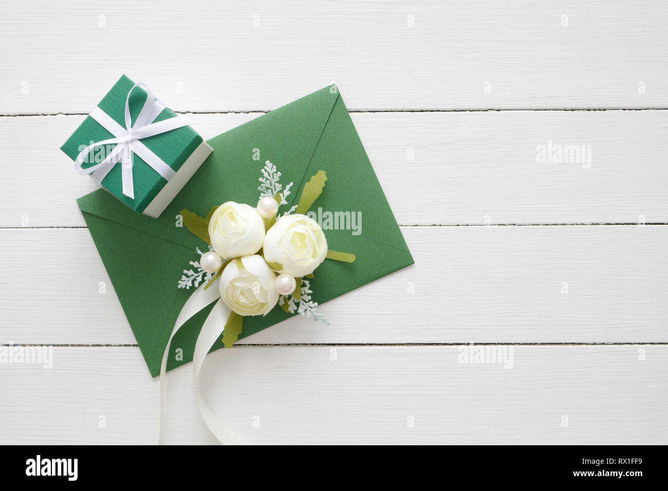 Invito a nozze card o il giorno di San Valentino lettera nella busta verde decorato con white rose fiori e confezione regalo. Lay piatto. Vista dall'alto. Copia spazio per Foto Stock