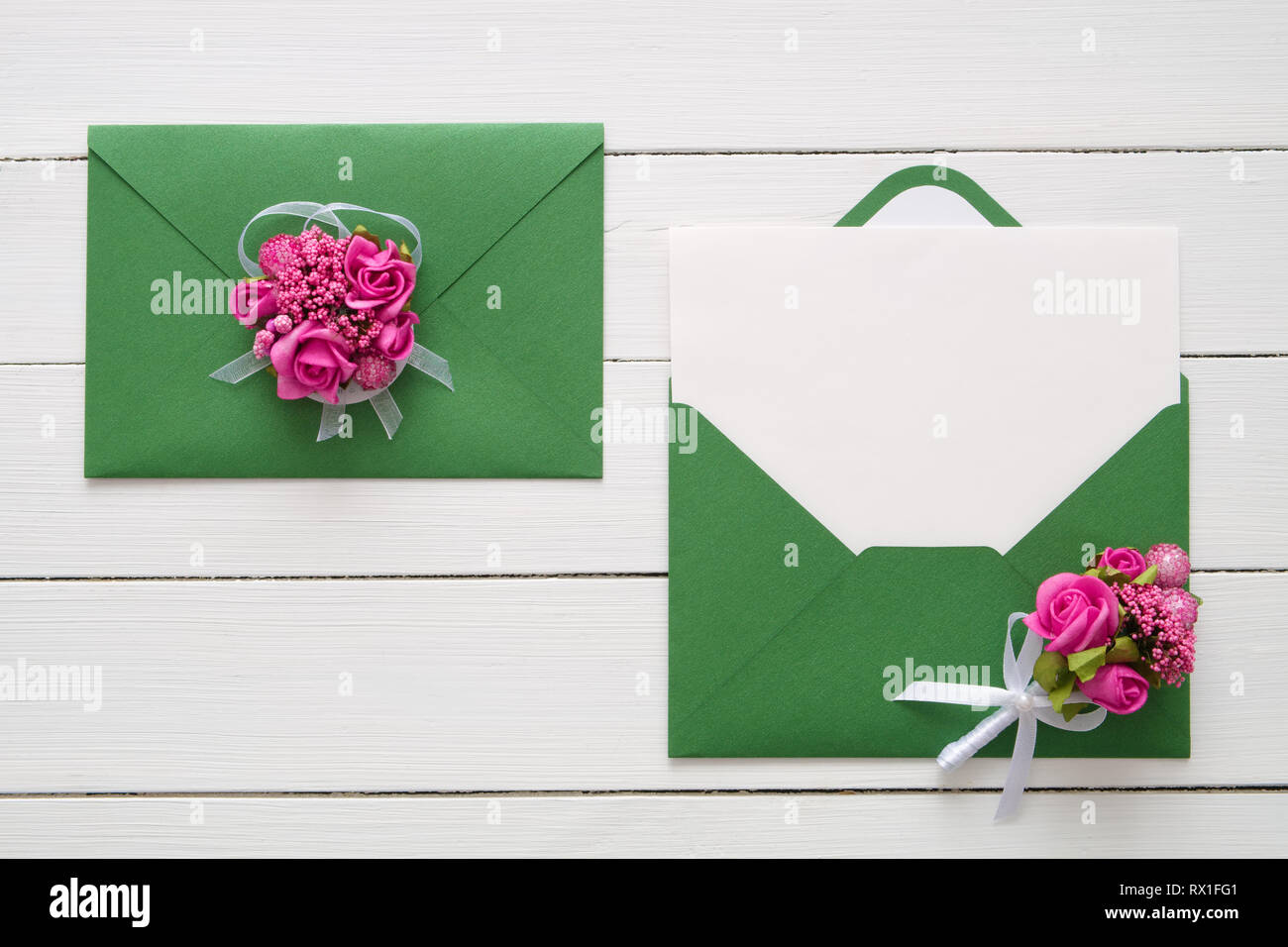 Invito a nozze le schede o il giorno di San Valentino lettere nelle buste verde decorata con rosa rosa fiori. Lay piatto. Vista dall'alto. Copia spazio per il testo. Foto Stock
