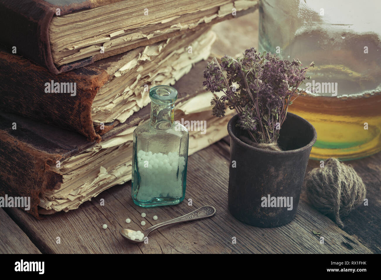 Pila di libri antichi, vintage mortaio di erbe medicinali, fiala di globuli omeopatici e tintura bottiglia. Foto Stock