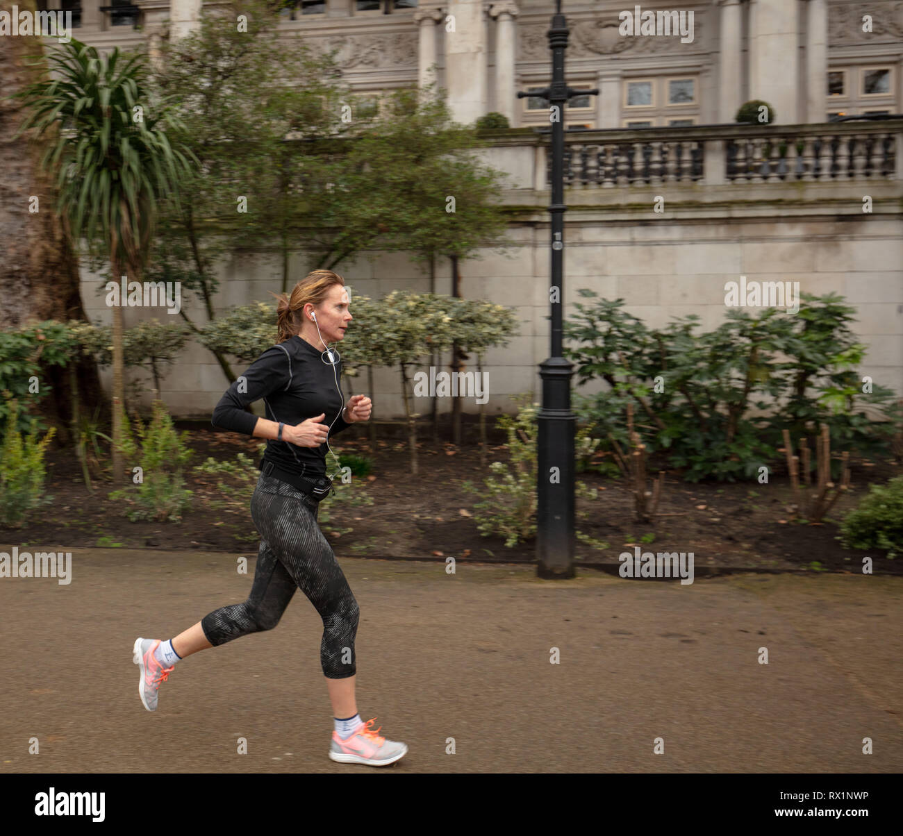 Donna esercizi e corre in Whitehall Gardens, London, Regno Unito in una fredda e blustery giorno nel mese di marzo. Foto Stock