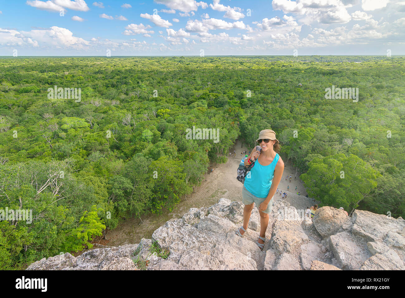 Angolo alto ritratto di donna che indossa gli occhiali da sole e cappello mentre si sta in piedi sul monte contro il verde paesaggio Foto Stock