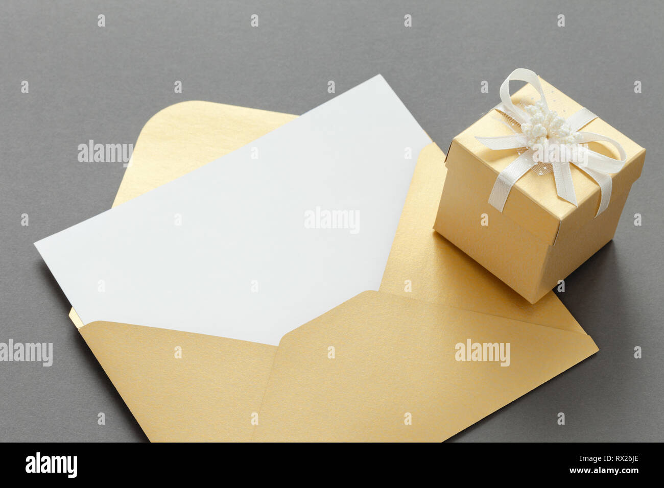 Aprire carta gialla busta vuota con foglio di carta e confezione regalo con nastro su sfondo grigio. Foto Stock
