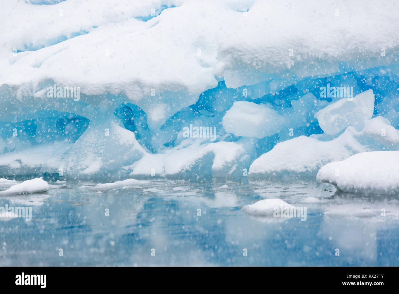 Un iceberg di messa a terra viene lentamente coperta di neve da una tempesta estiva vicino a Pleneau Island, Pleneau Island, Lemaire Channel, Penisola Antartica Foto Stock