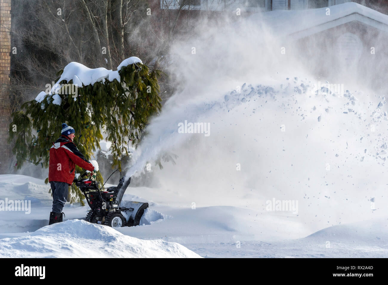 Oakville, Ontario, Canada il 25 dicembre 2017. Uomo con uno spalaneve pulizia di un vialetto dopo la mattina di Natale tempesta di neve Foto Stock