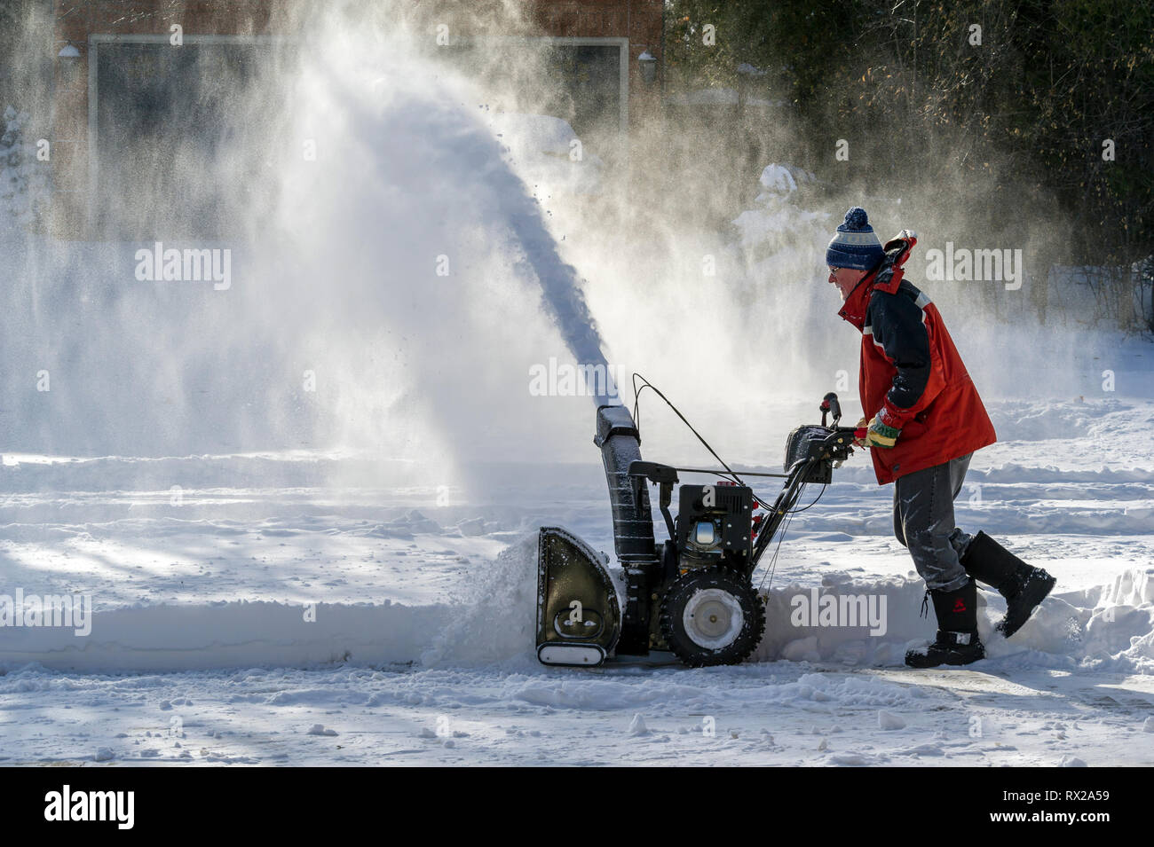 Oakville, Ontario, Canada il 25 dicembre 2017. Uomo con uno spalaneve pulizia di un vialetto dopo la mattina di Natale tempesta di neve Foto Stock