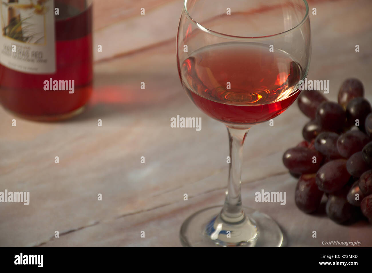 Bicchiere di vino rosso con la bottiglia e grappolo di uva rossa sulla tavola  di marmo Foto stock - Alamy