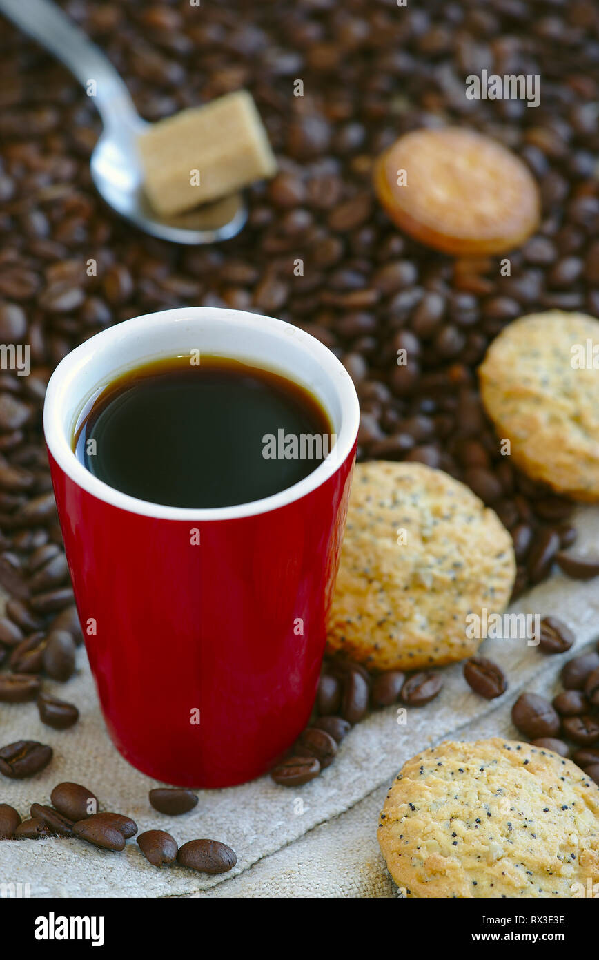 Red tazza da caffè, caffè sfuso in grani e i cookie Foto Stock