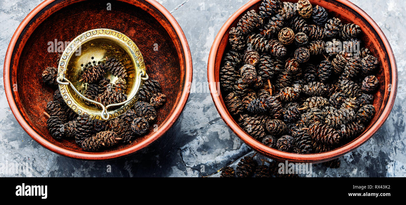 Coni di guarigione di ontano in un mortaio.Alder piantine.medicine a base di erbe Foto Stock