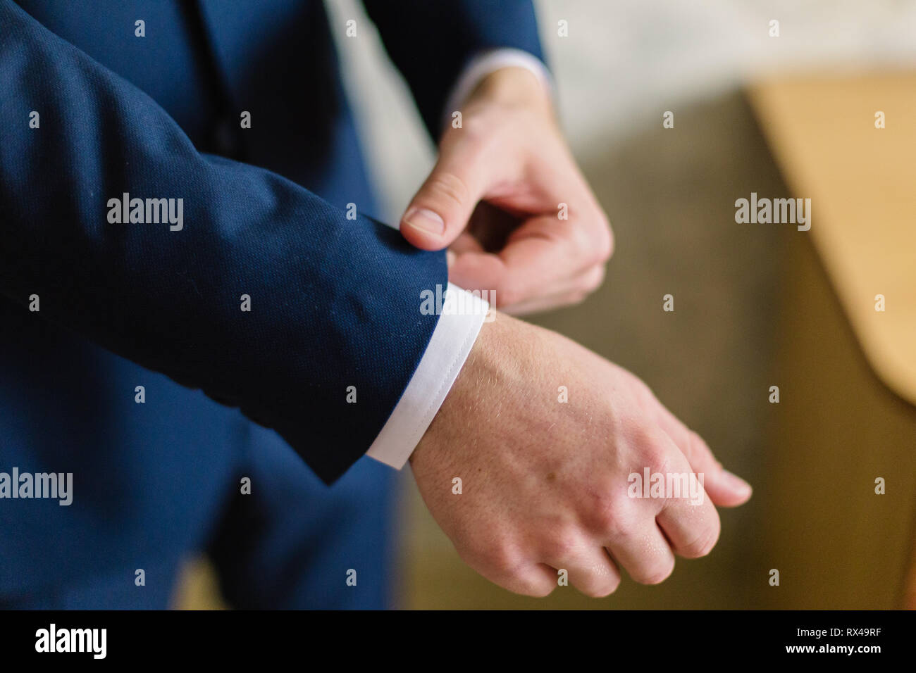 Imprenditore in una camicia bianca si raddrizza polsini, in piedi presso la finestra nella luce naturale. Uomo bracciale pulsanti-link sul francese polsini maniche bianche di lusso Foto Stock