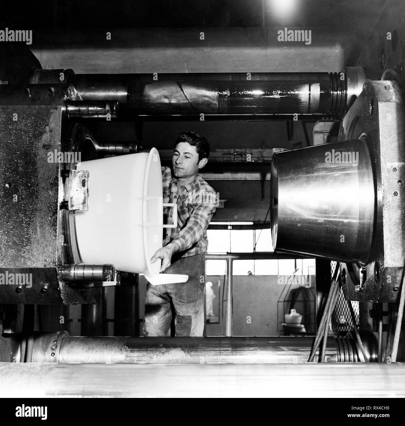 Lavoratore lo stampaggio di un secchio di plastica, 1959 Foto Stock