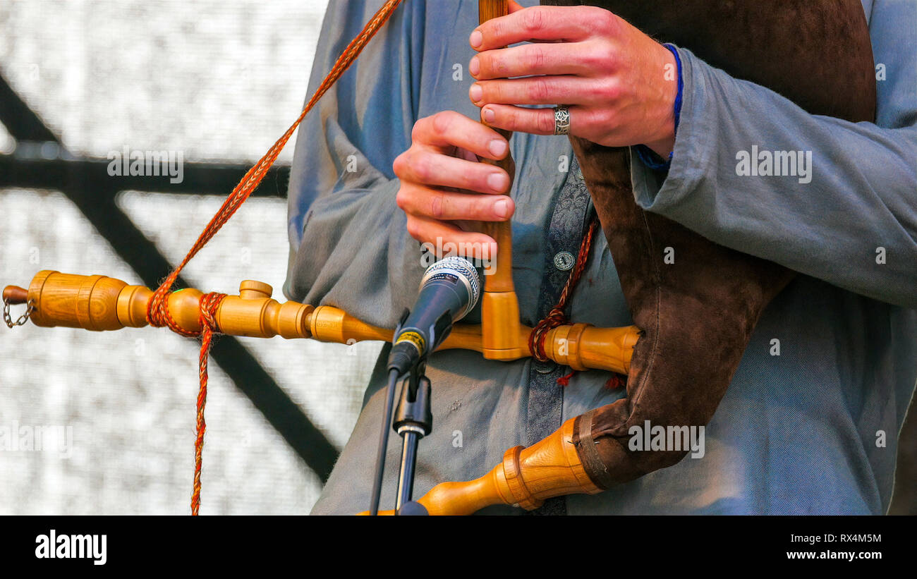 Suonare il flauto con altri strumenti sul suo collo. Durante la riproduzione il flauto l uomo ha altri strumenti appeso sul suo corpo sono stru in legno Foto Stock