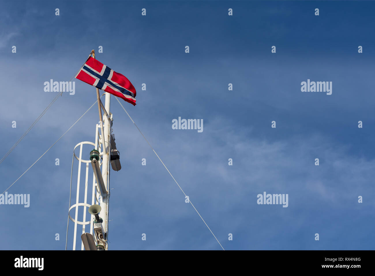 Bandiera norvegese su un pennone contro un cielo blu. Tempo soleggiato in Norvegia Foto Stock