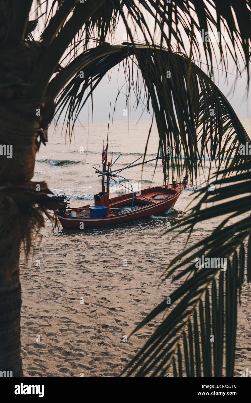 Tradizionale Tailandese di coda lunga barca da pesca sotto le palme sulla spiaggia di Hua Hin all'alba. Foto Stock