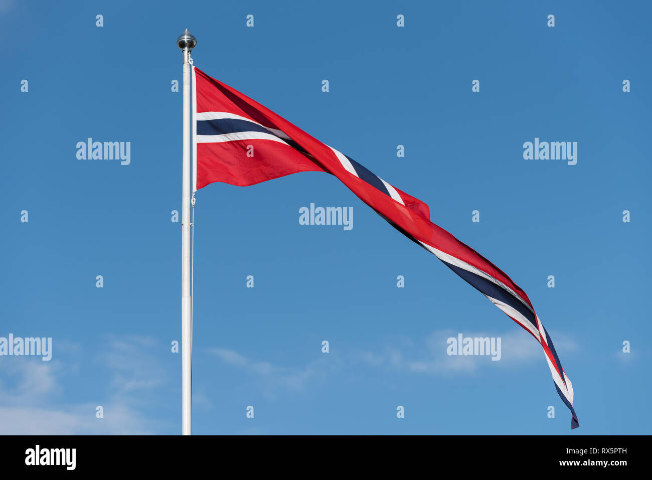 Bandiera norvegese su un pennone contro un cielo blu. Tempo soleggiato in Norvegia Foto Stock