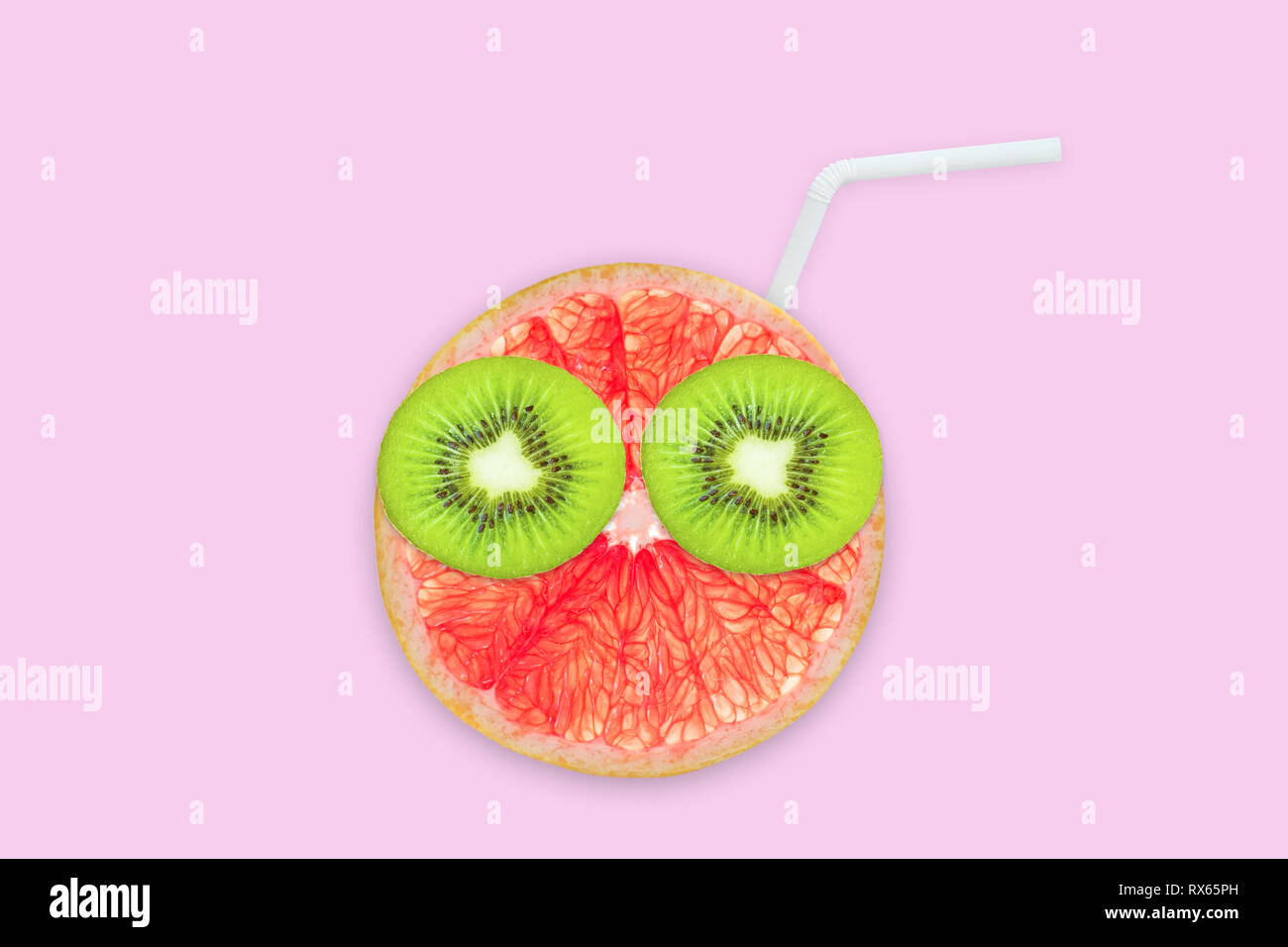 Frutta faccia creativa con fette di pompelmo e kiwi, cannuccia su sfondo rosa, succo di frutta e il concetto di estate Foto Stock