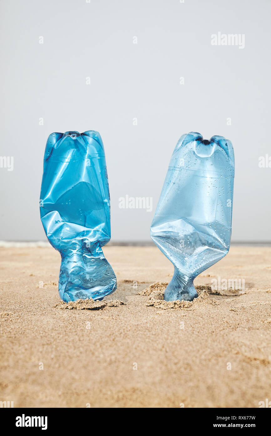 Due bottiglie di plastica bloccati nella sabbia sulla spiaggia, il fuoco selettivo, tonificazione del colore applicato. Foto Stock