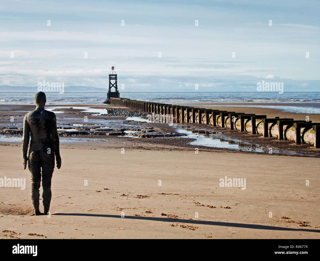 Uno di Antony Gormley ferro di uomini in piedi in un altro luogo sulla Crosby Beach Foto Stock