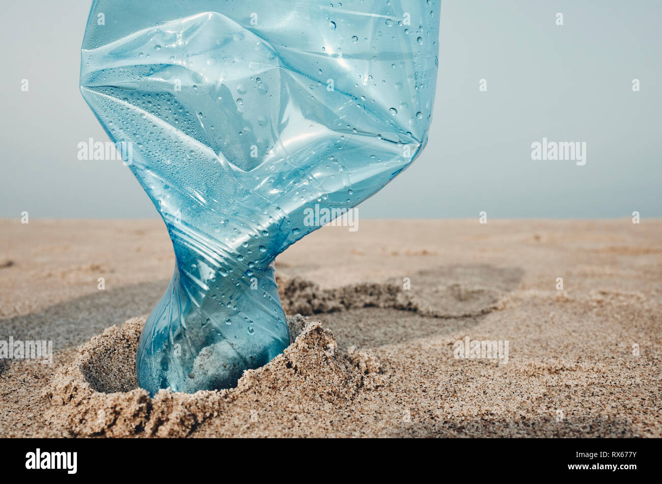Chiudere l immagine di una bottiglia di plastica bloccati nella sabbia sulla spiaggia, il fuoco selettivo, tonificazione del colore applicato. Foto Stock