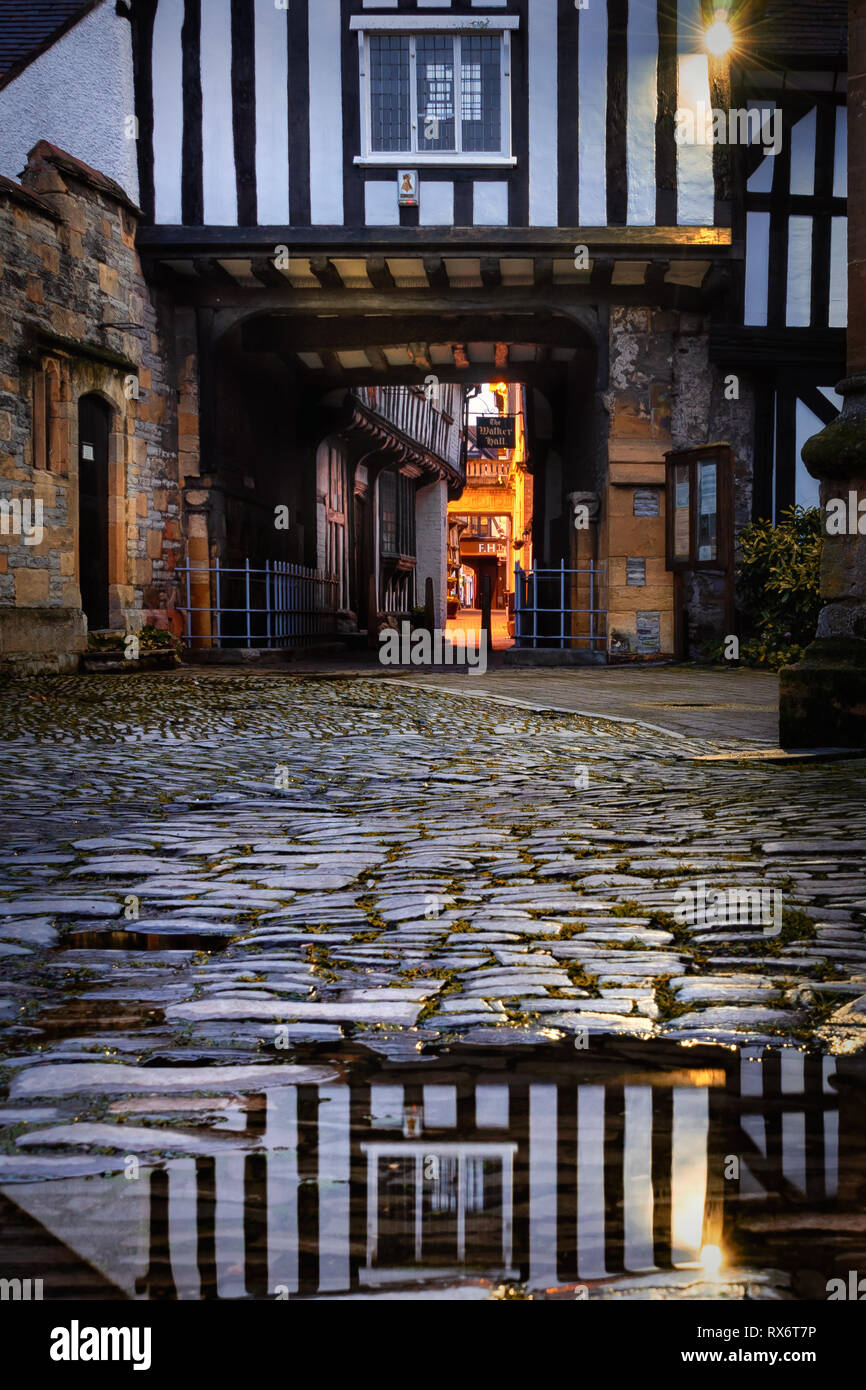 Evesham in worcestershire vialetto attraverso la struttura di legno edificio con la riflessione sulla strada acciottolata Foto Stock