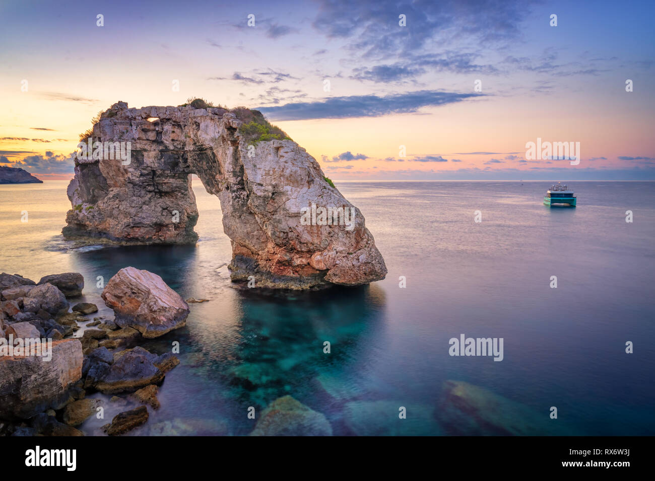 Es Pontas in Mallorca con barca ancorata nelle vicinanze del mare Mediterraneo. Sunrise con yacht e arco di roccia vicino a Santanyi Maiorca Foto Stock